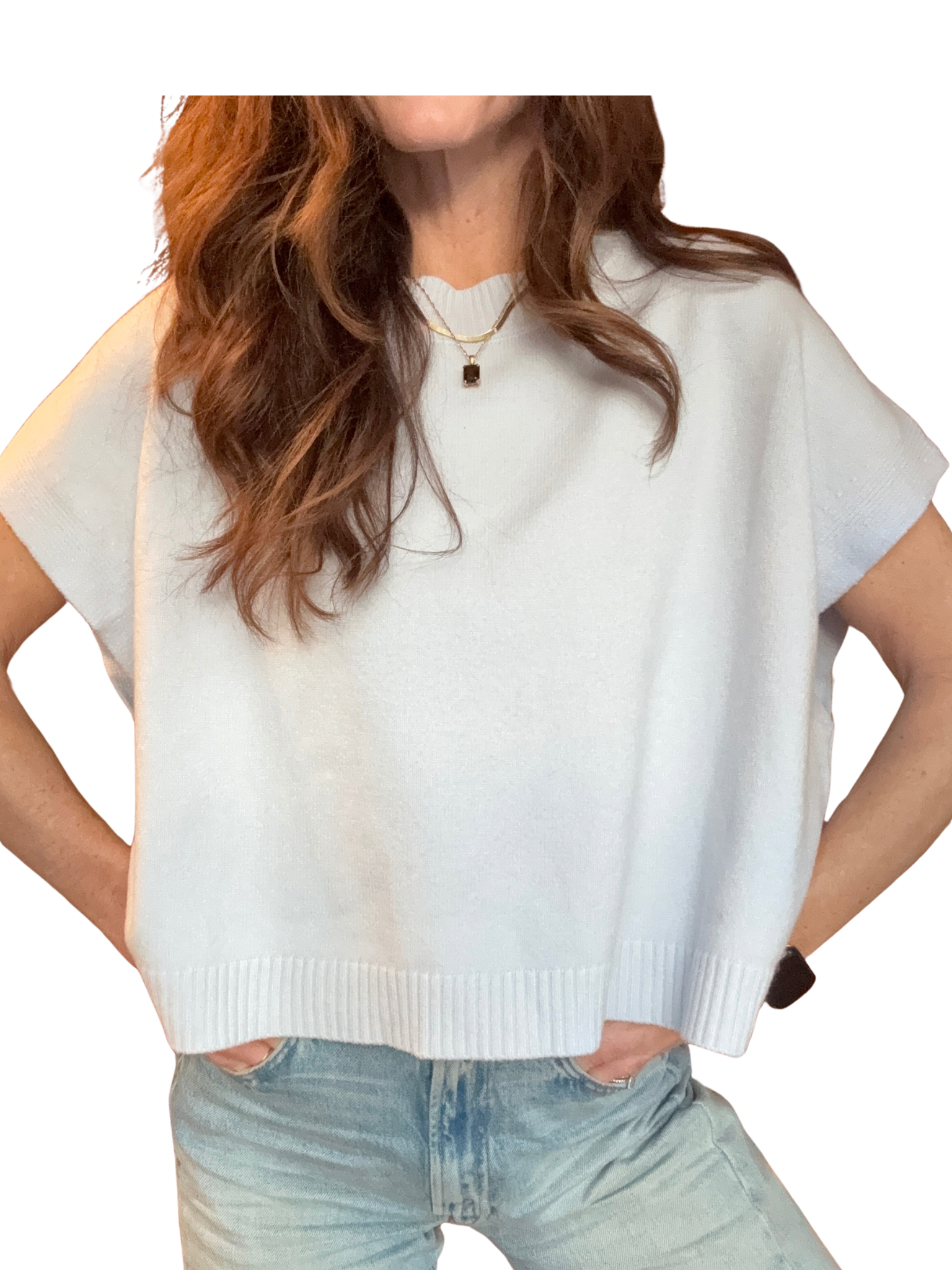 Person wearing a light blue knit short sleeve sweater over a white shirt with light blue jeans on a white background