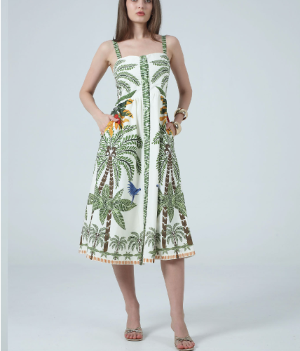 Woman wearing a tropical print dress with palm trees and flowers on a plain background