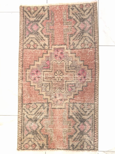 Patterned Turkish rug with pink and beige colors on a white floor.