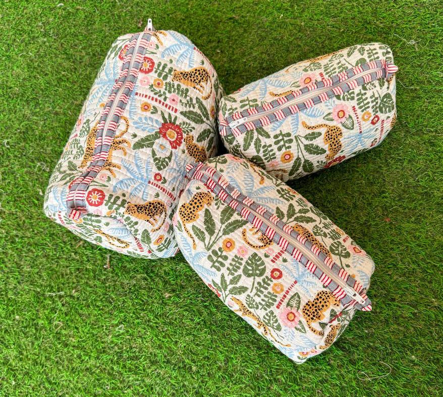 Three  quilted fabric cosmetic bags with a colorful animal leopard and floral pattern on a green grass-like surface.